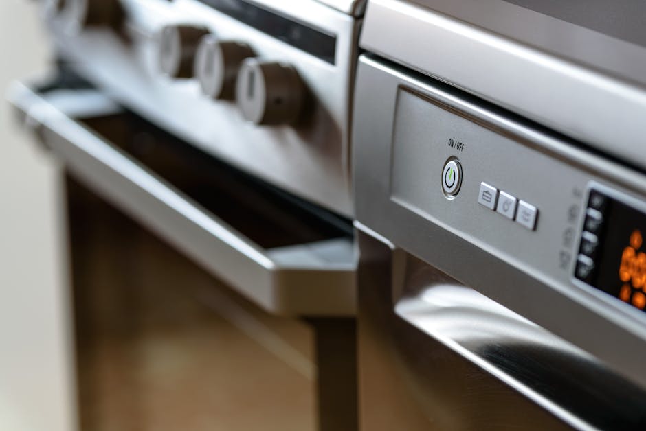 Close-up of a person wearing yellow and blue rubber gloves, using their hands to handle a wire rack inside an oven on Lonsdale Road Queens Park. The oven interior appears clean and free of food debris